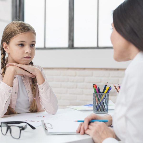 young-child-psychologist-talking-with-sad-little-girl-office